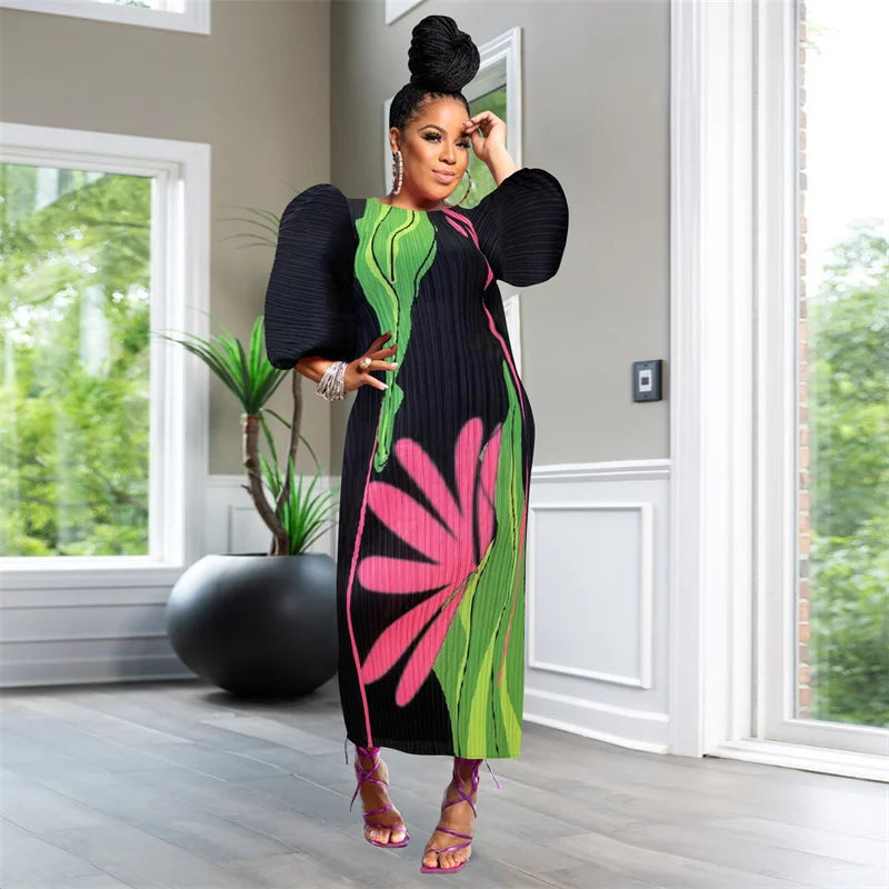 Woman in a colorful dress standing in a room with large windows and a plant.