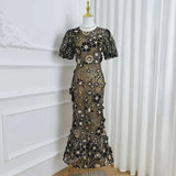 Elegant black floral lace dress on a mannequin against a white curtain.