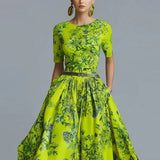 Woman wearing a bright green floral dress against a gray background