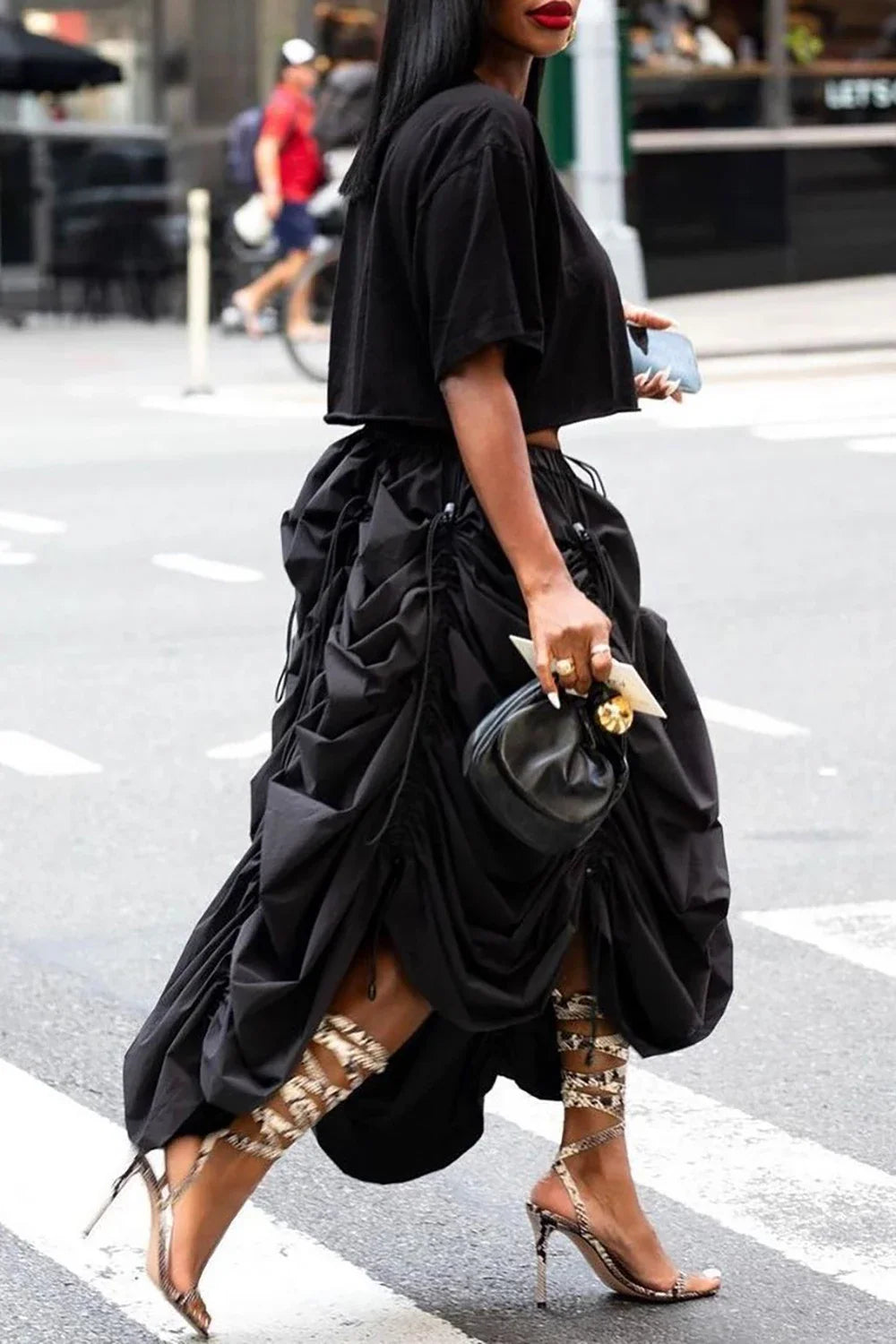 Woman in black outfit with large skirt crossing street
