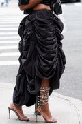 Person wearing a black, ruched skirt with high-heeled shoes on a city street.