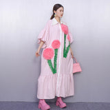 Woman wearing a pink dress with floral designs against a gray background