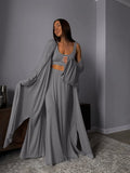 Woman wearing a long gray dress standing in a room with a gray wall.