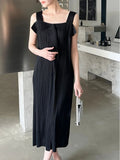 Woman wearing a black dress holding a clutch in an indoor setting.