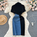Black top and blue jeans on a mannequin with decorative items like a hat and necklace on a textured surface.