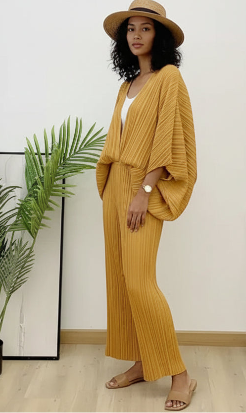 Person wearing a mustard yellow outfit standing indoors with a plant in the background