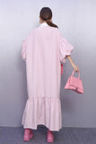 Person wearing a pink striped dress holding a matching pink handbag against a gray background