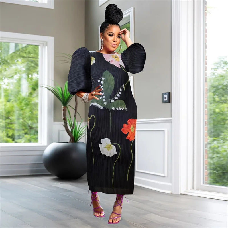 Woman in a floral dress standing in a room with large windows and a plant.