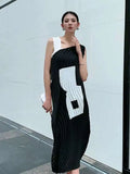 Woman wearing a black and white dress with geometric patterns in an urban setting.
