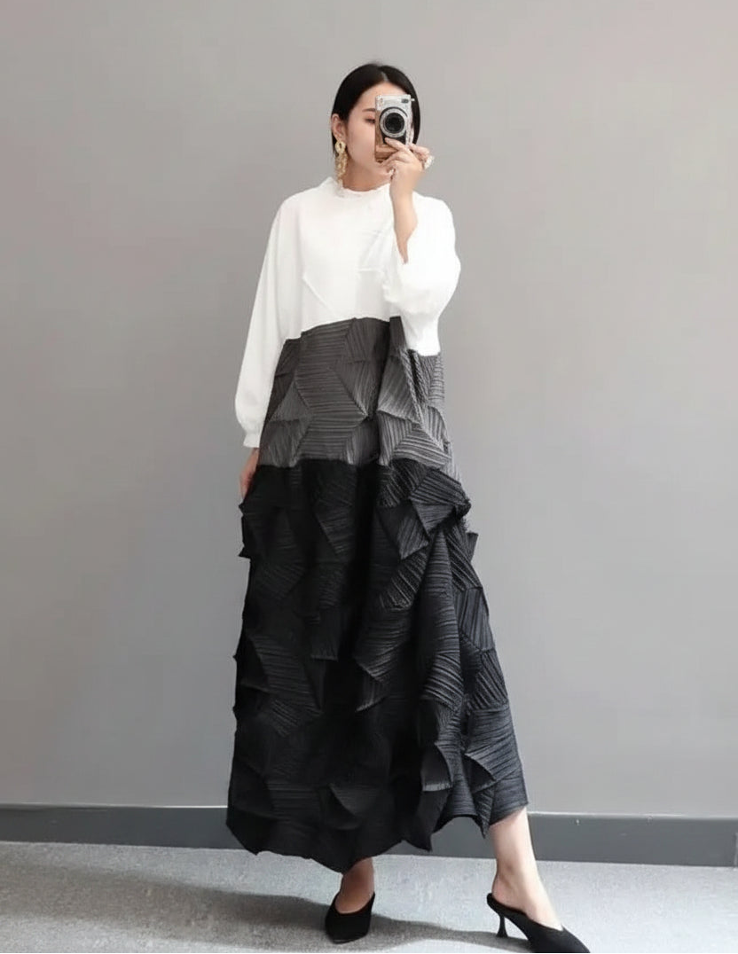Person wearing a white blouse and black ruffled skirt in a minimal indoor setting.