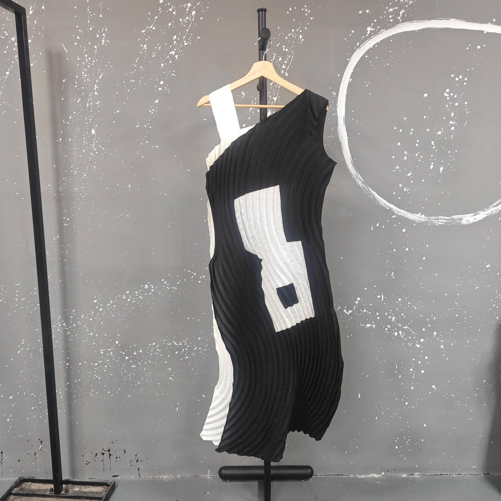 Black and white dress on a mannequin against a gray wall with white circular design.