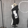 Black and white dress on a mannequin against a gray wall with white circular design.