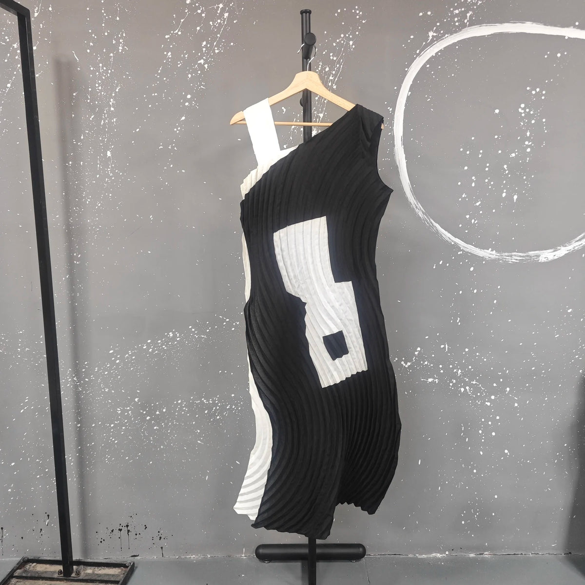Black and white dress on a mannequin against a gray wall with white circular design.
