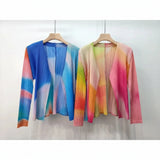 Two colorful cardigans on hangers with a plain background