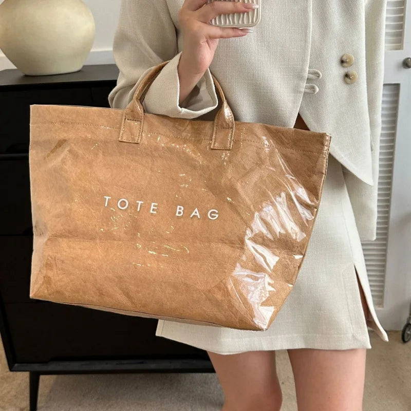 Person holding a brown tote bag with 'TOTE BAG' text.