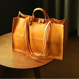 Brown leather handbag on a wooden table with 'Peshawar' branding.