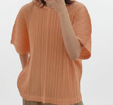 Person wearing an orange pleated top with a blurred background