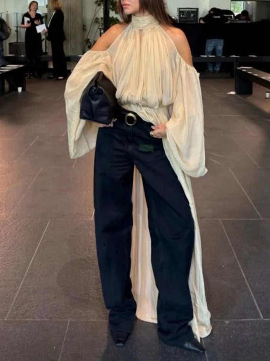 Person wearing a cream blouse with wide sleeves and black pants in an indoor setting.
