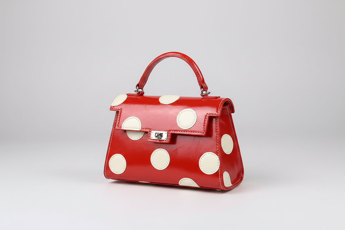 Red handbag with white polka dots on a beige surface
