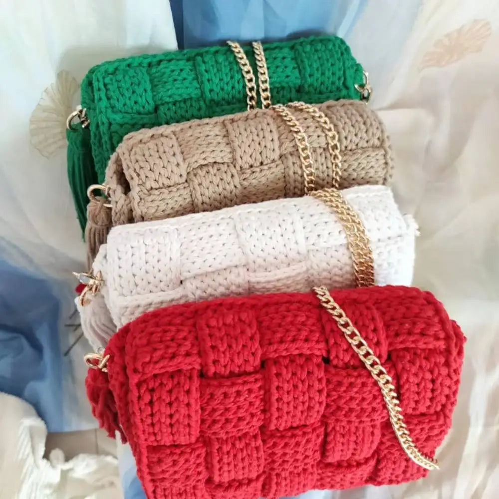 Stack of colorful knitted purses with gold chains on a light background