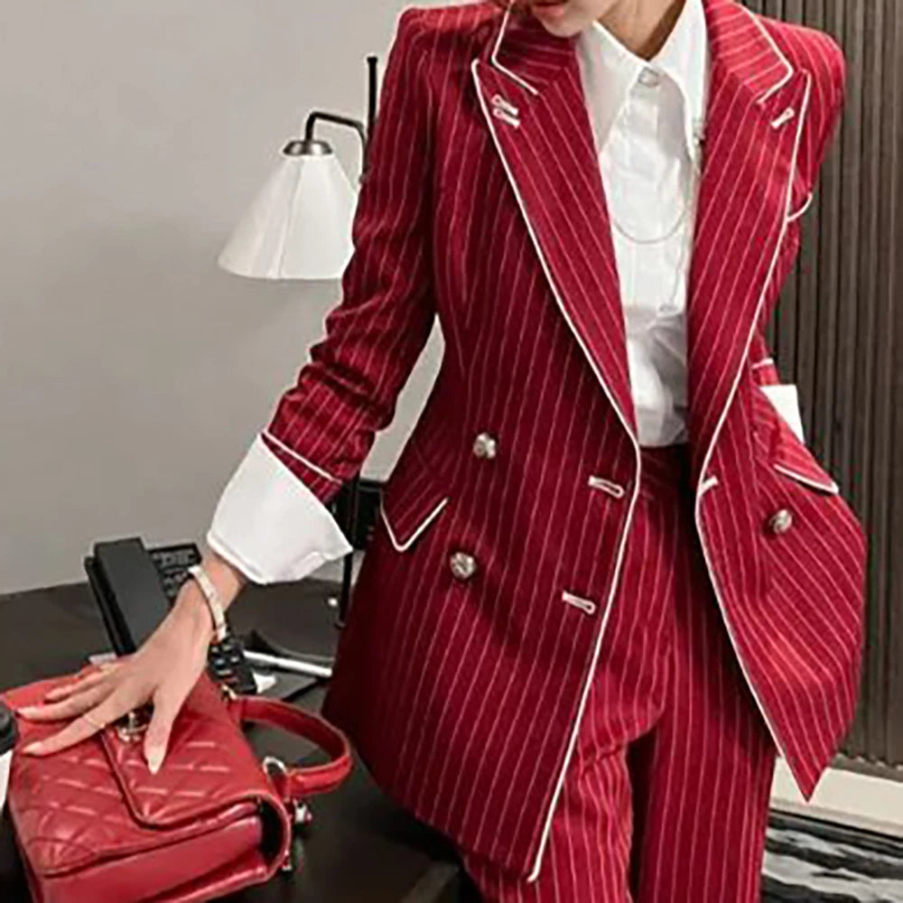 Person wearing a red pinstripe suit holding a red handbag indoors.