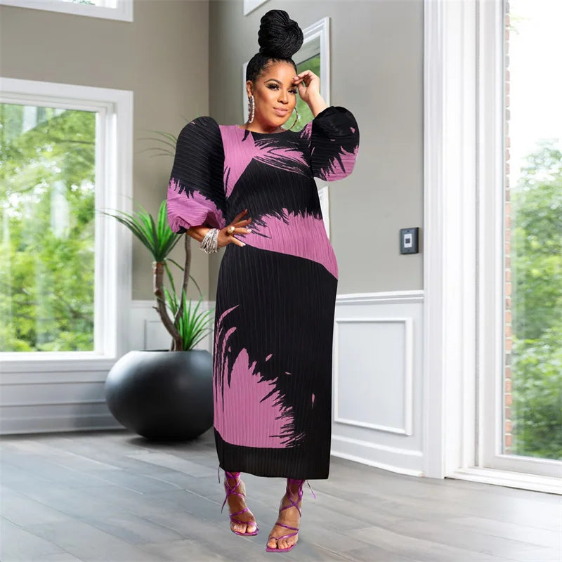 Woman in a black and pink dress standing in a room with large windows and a plant.