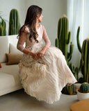 Woman in a white dress sitting on a couch with a cactus plant in the background