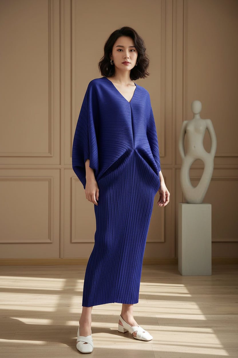 Person wearing a blue knit outfit standing indoors with a plant in the background
