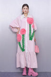 Person wearing a pink dress with floral designs against a plain background