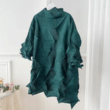 Green textured dress on a hanger against a white wall