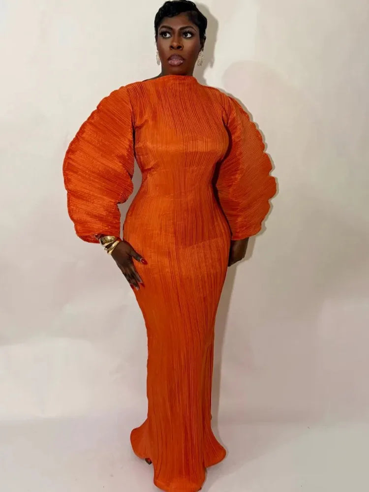 Person wearing an orange pleated dress against a white background