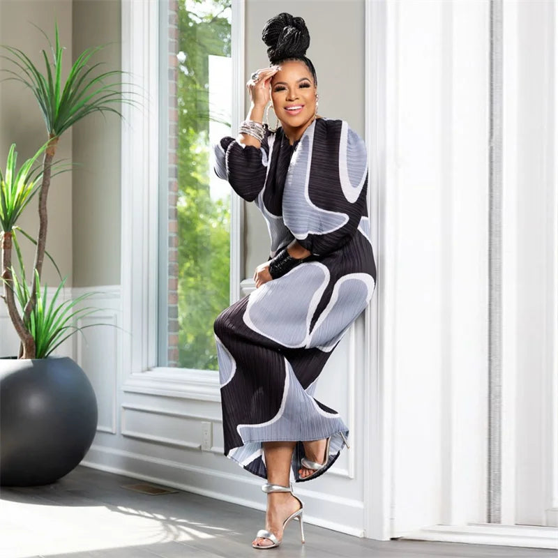 Woman in a stylish black and white outfit standing in a bright room with large windows.