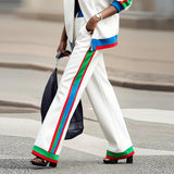 Person wearing white pants with colorful stripes walking on a street.