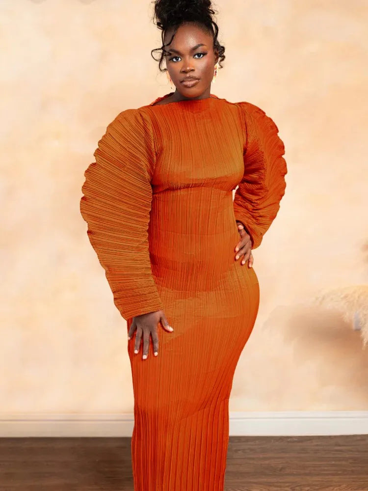 Woman wearing an orange pleated dress against a beige background