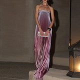 Woman in a strapless purple gown holding a clutch against a neutral background
