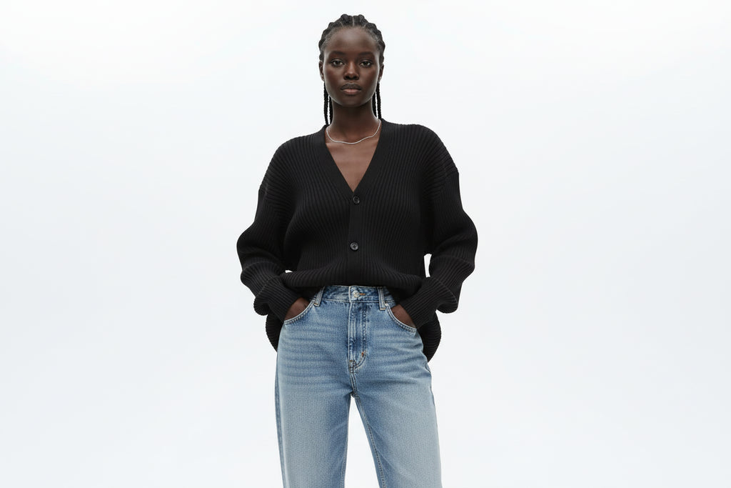 Person wearing a dark ribbed sweater with a blurred background