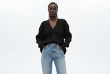 Person wearing a dark ribbed sweater with a blurred background