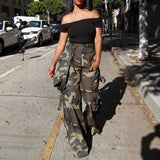 Woman wearing a black off-shoulder top and camouflage pants walking on a city street.
