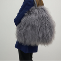Person holding a fluffy gray handbag against a plain background