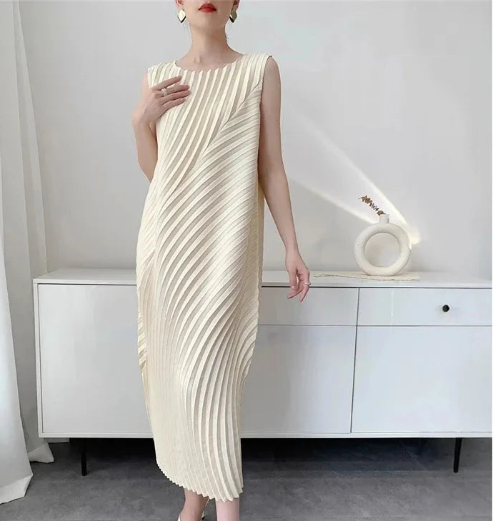 Woman wearing a cream pleated dress in a minimalistic room.