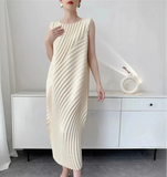 Woman wearing a cream pleated dress in a minimalistic room.