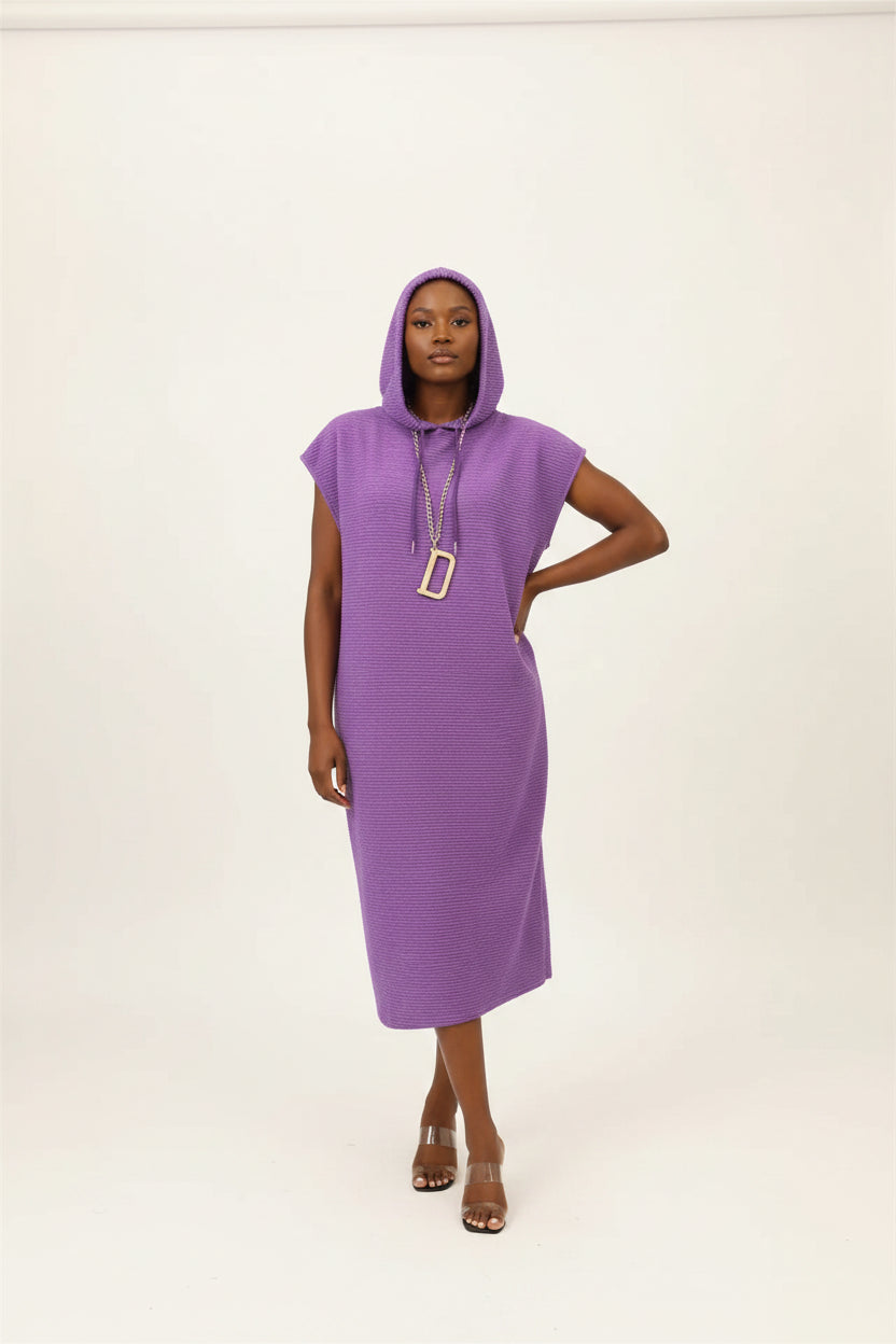 Purple sleeveless dress on a hanger with a plant in the background