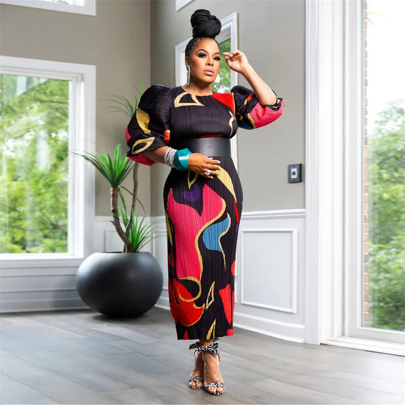 Woman in a colorful dress standing in a modern room with large windows.