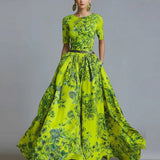 Woman wearing a bright green floral dress with a gray background, featuring the brand 'ZJASXMS'.