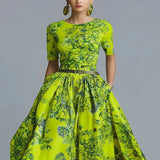 Woman wearing a bright green floral dress against a gray background