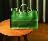 Green leather handbag on a wooden table with a dark curtain background