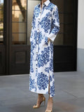 Woman wearing a long blue and white floral dress standing in front of a building entrance.