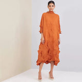 Woman wearing an orange dress with a textured pattern against a plain background