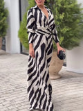 Woman wearing a zebra print dress standing outdoors with greenery in the background