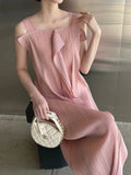 Woman wearing a pink pleated dress holding a white handbag.